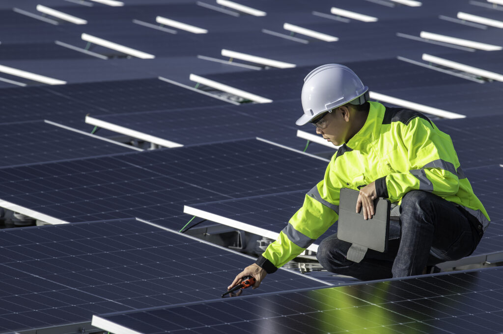 Engineer inspecting solar panels at a solar farm, focused on renewable energy solutions.