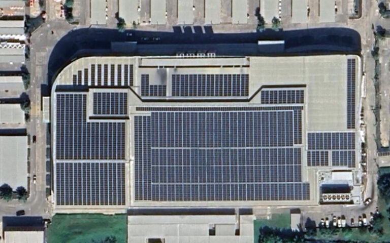 Aerial view of a large commercial building with extensive solar panel installation on its roof.