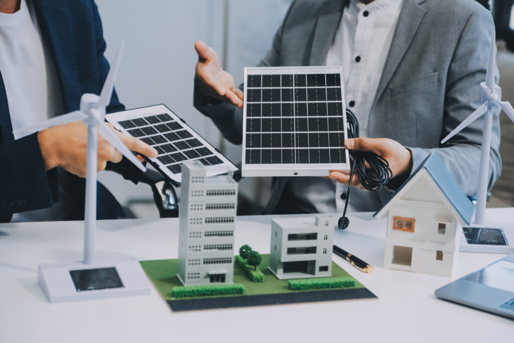 Businessmen discussing solar panel installation with building models