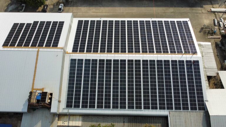 Aerial view of solar panels installed on the roof of a factory building.