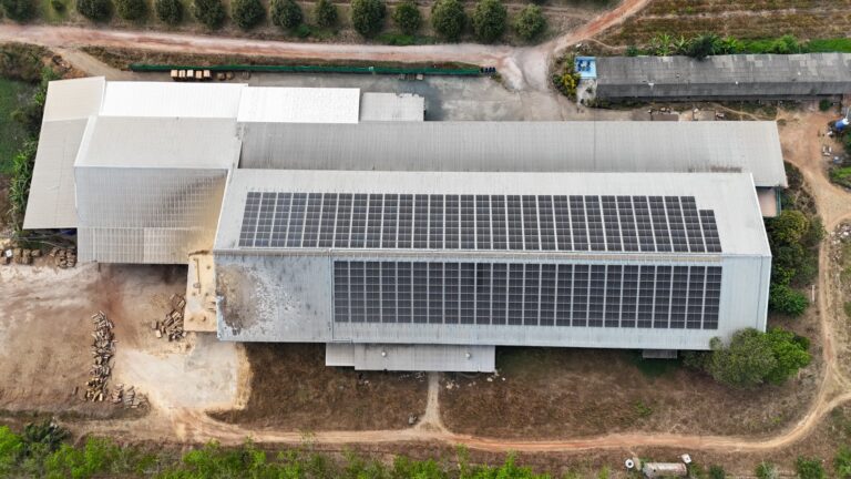 Aerial view of a factory with a large solar panel installation on the roof.