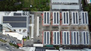 Aerial view of a factory with extensive solar panel installations on rooftops and solar farms.