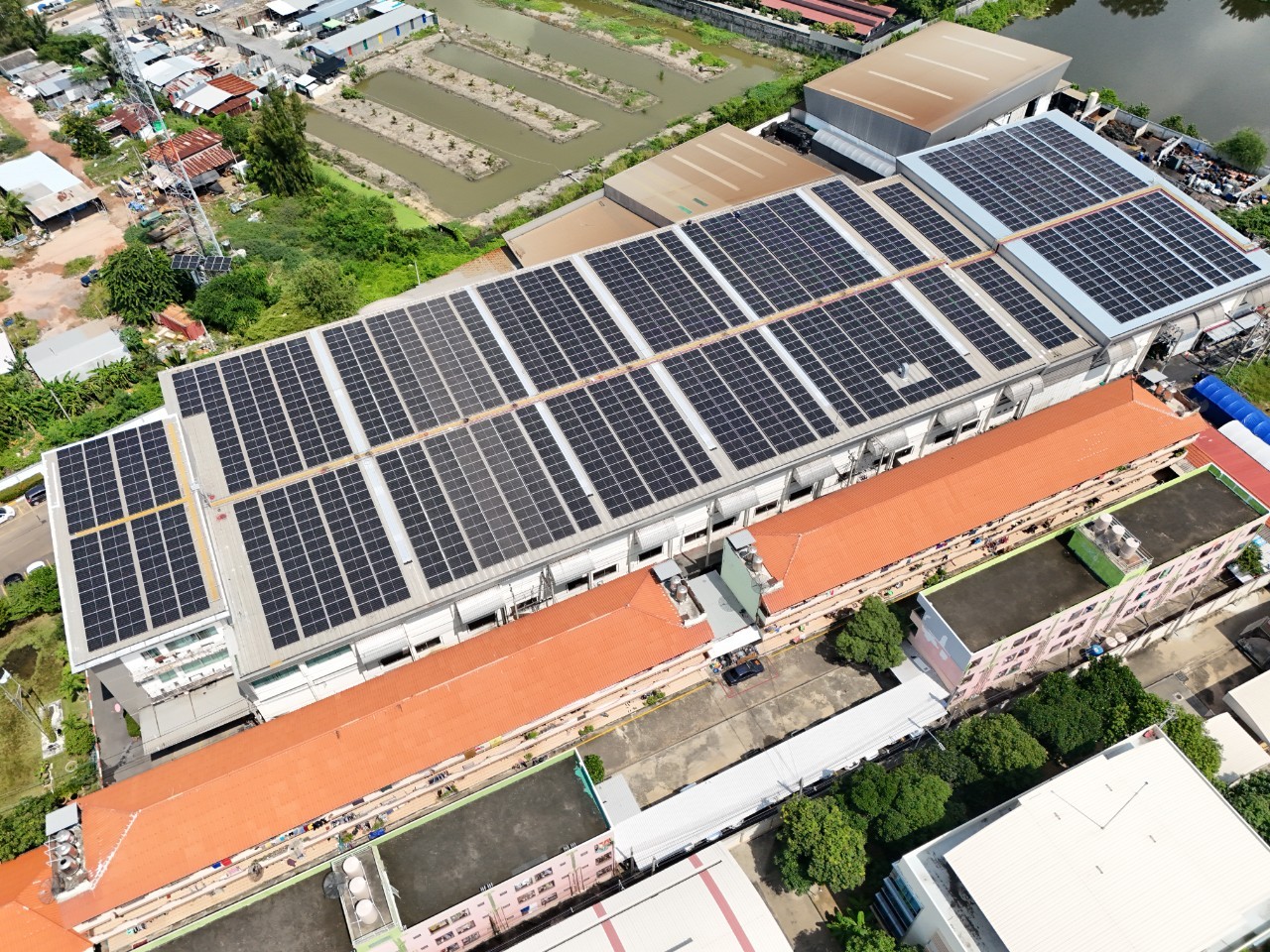 Aerial view of a large industrial building with extensive solar panel installation.