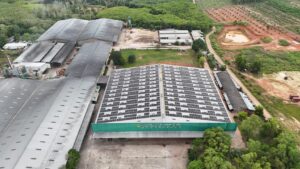 Aerial view of a factory with a large rooftop solar panel installation.