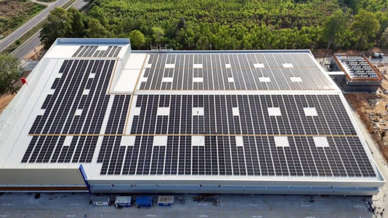 Aerial view of a large warehouse roof covered in solar panels, showcasing renewable energy installation.