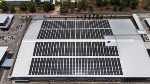 Aerial view of a large industrial building with extensive solar panel installation on the roof.