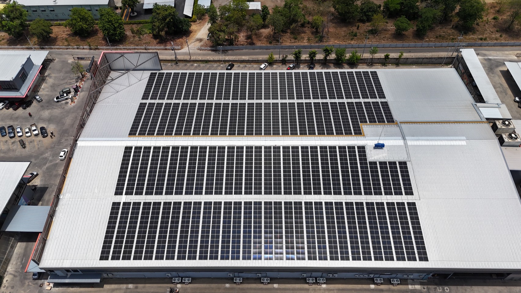 Aerial view of a large industrial building with extensive solar panel installation on the roof.