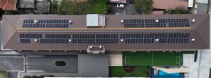 Aerial view of a school building with extensive solar panel installation on its roof.