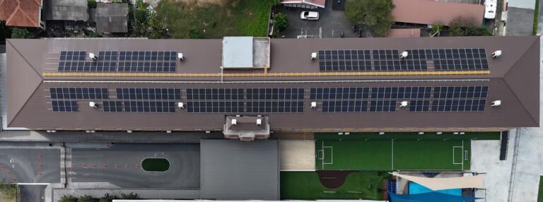 Aerial view of a school building with extensive solar panel installation on its roof.